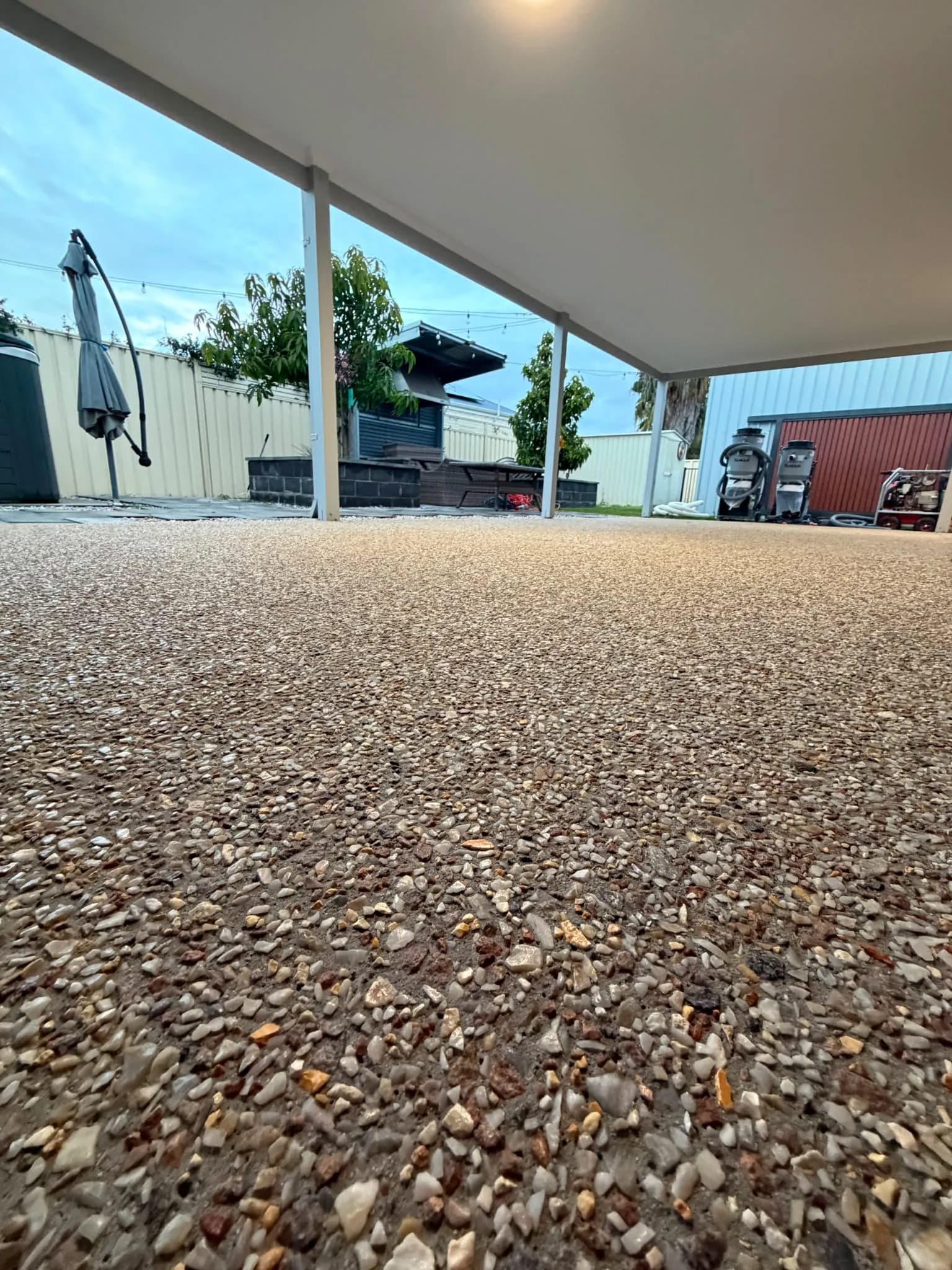 Rough exposed aggregate alfresco in Perth before honing, with grinding equipment on site